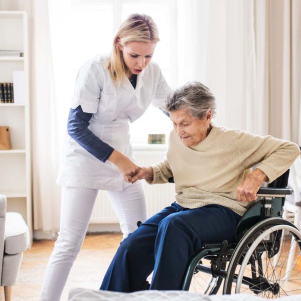 Caregiver assisting senior woman to stand